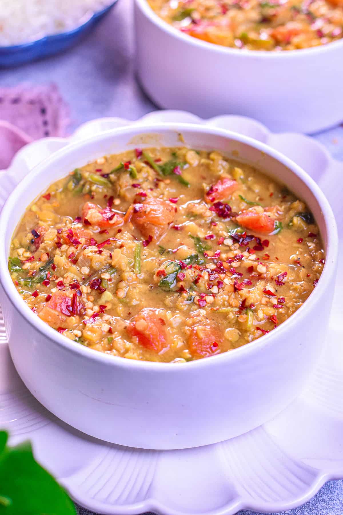 A bowl of hearty red lentil and spinach soup with a rich, golden-orange color.