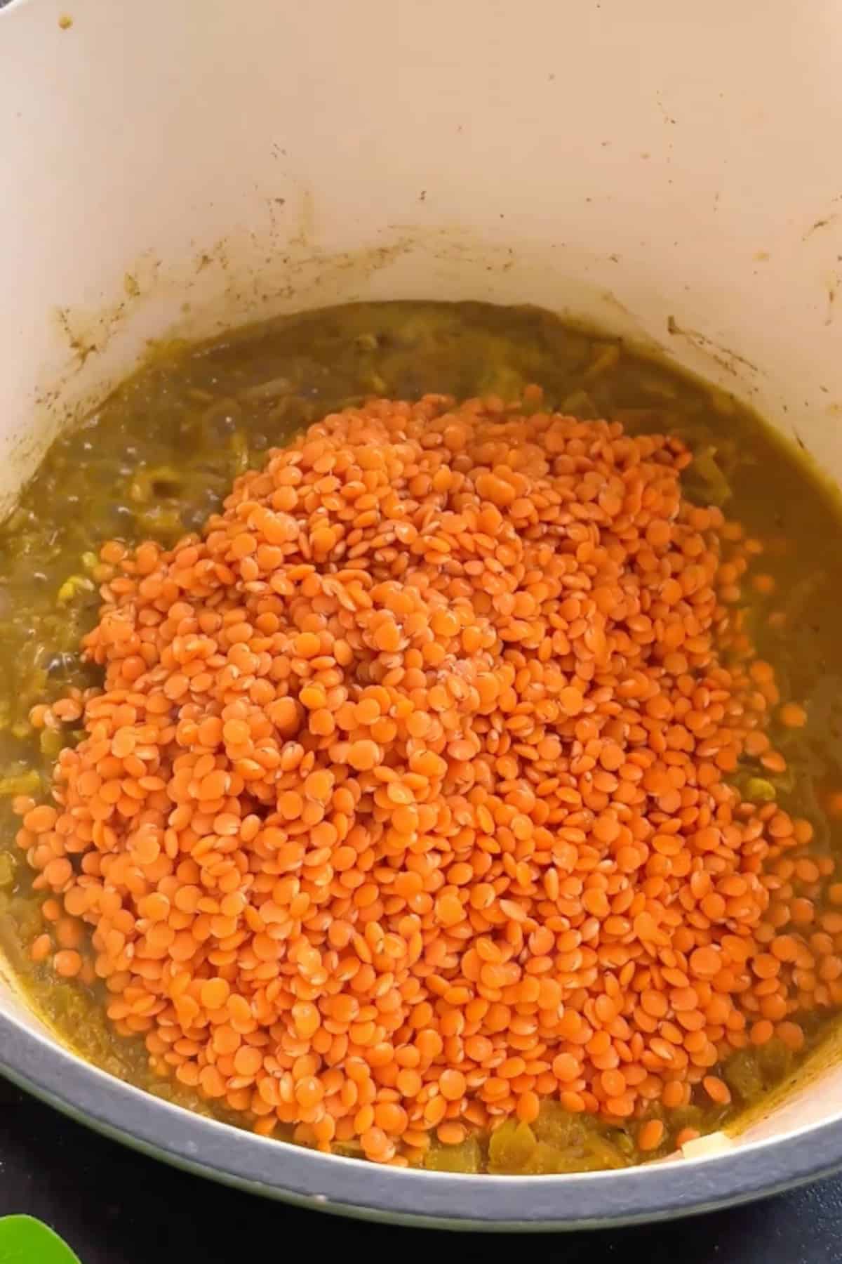 Spices being stirred into a pot while cooking.