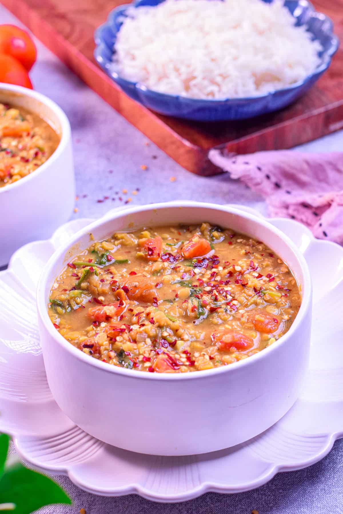 A bowl of hearty red lentil and spinach soup with a rich, golden-orange color.