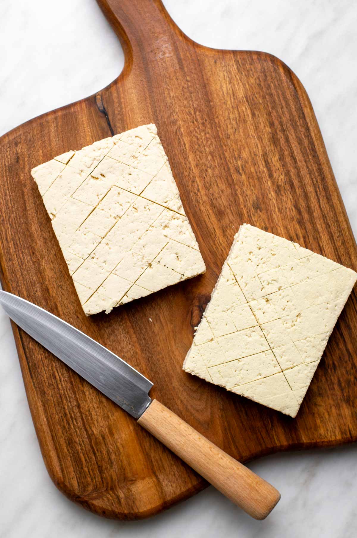 Sliced tofus on a chopping board and a knife.