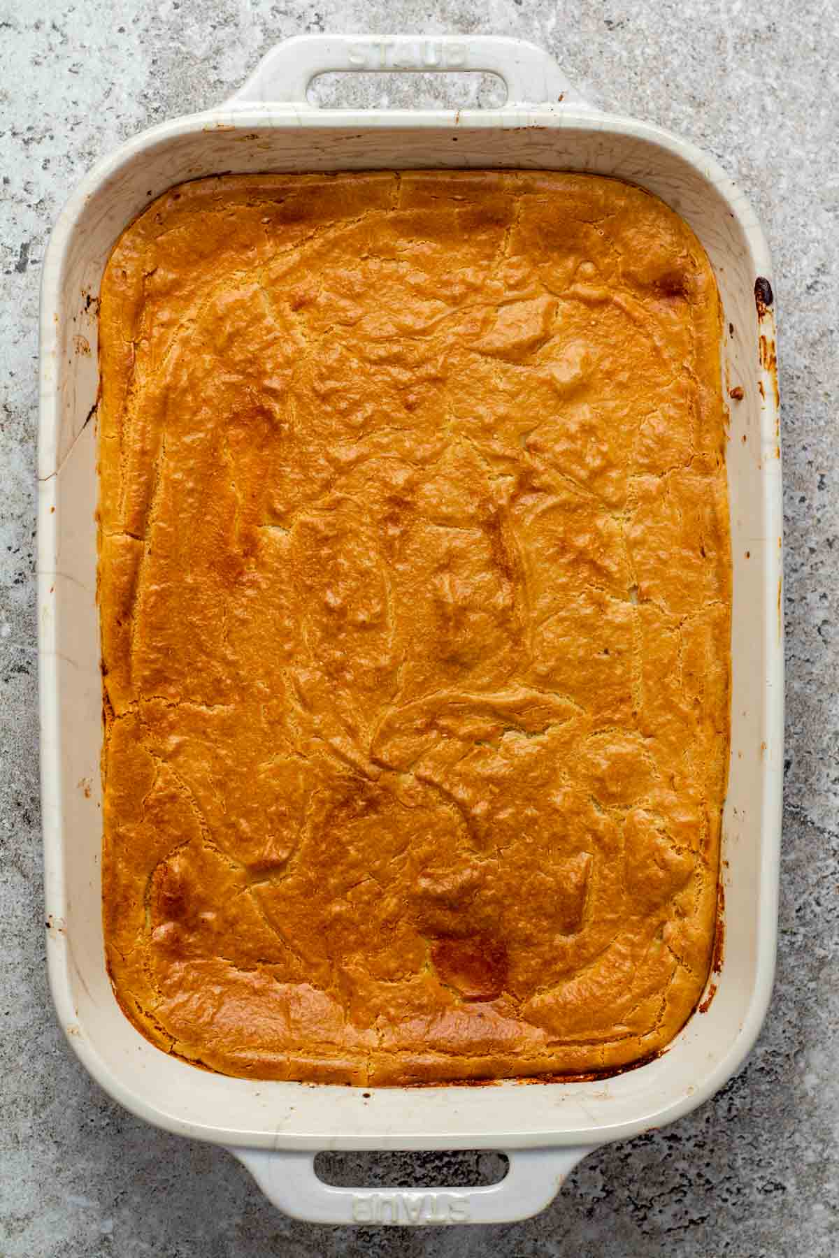 Freshly baked vegan moussaka in a white baking dish with a golden, creamy cashew béchamel top.