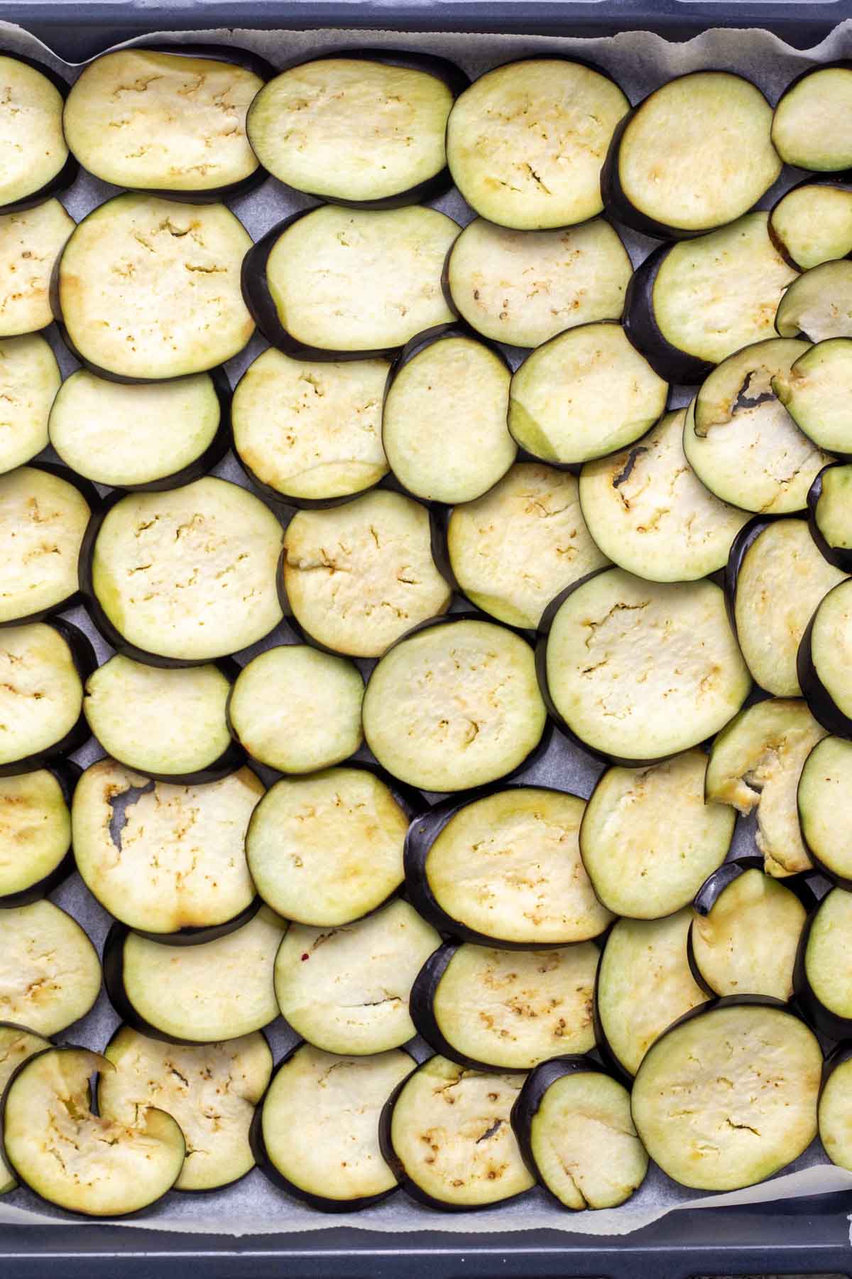Sliced eggplants arranged on baking tray.