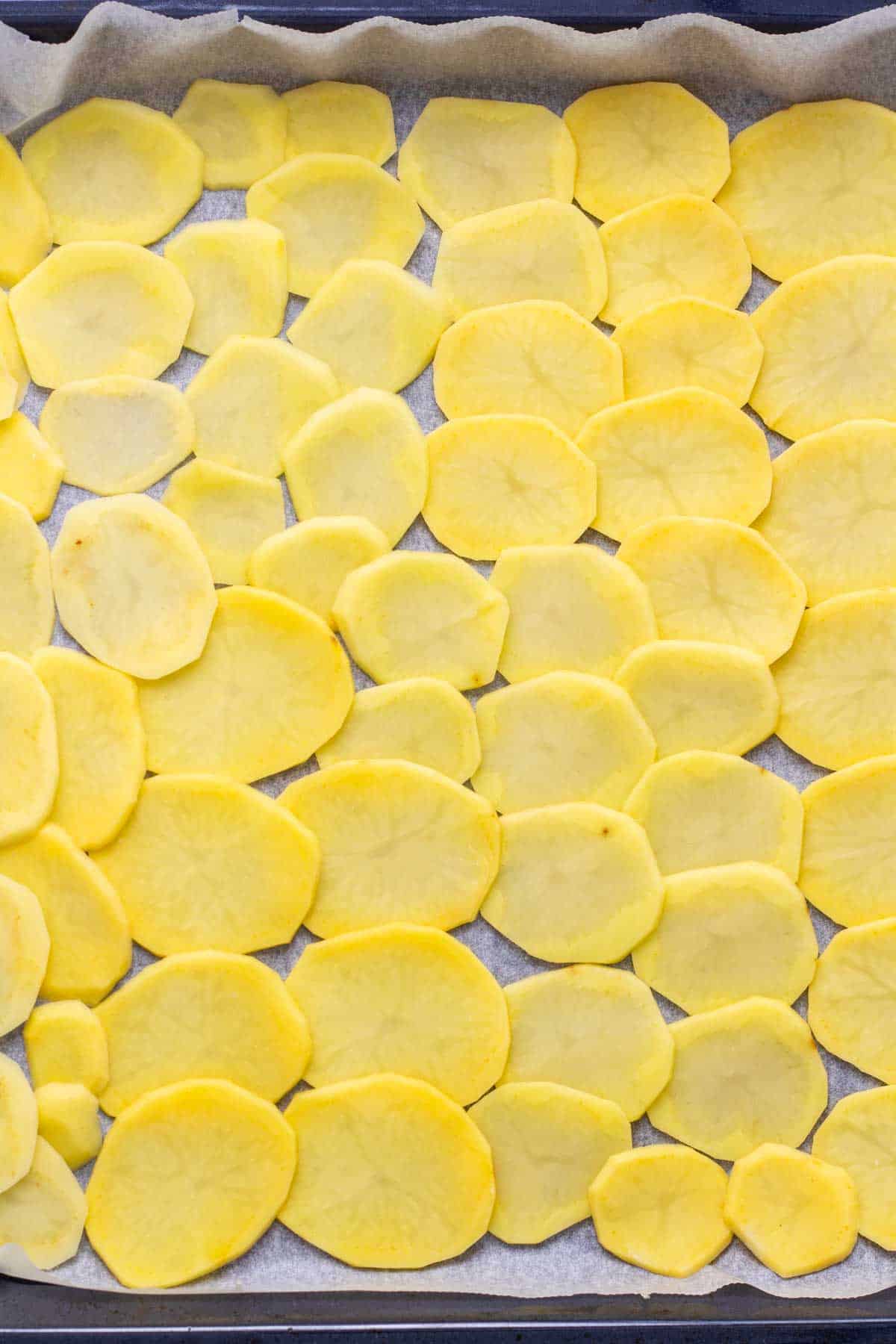 Sliced potatoes on a baking tray.